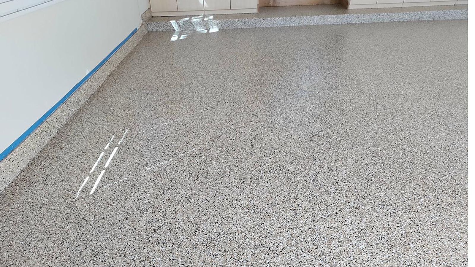 Warm tan and brown flake epoxy floor with a glossy finish in a Colorado home