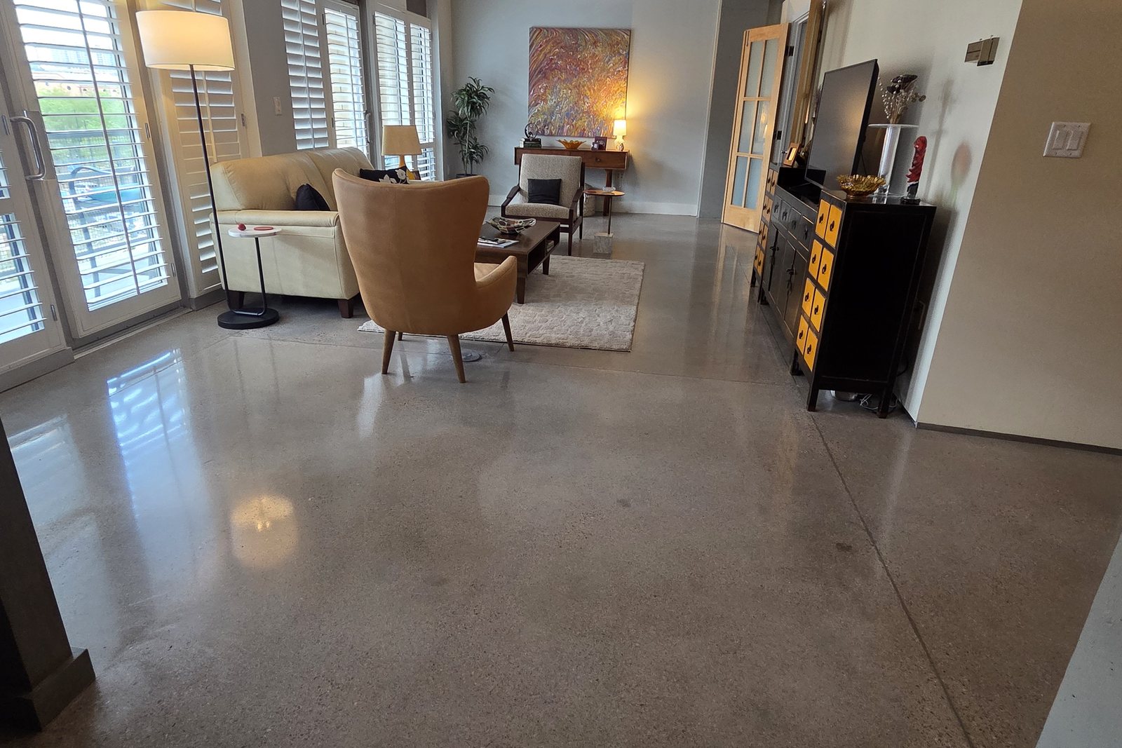 Polished concrete living room floor in a Denver-area loft with light salt-and-pepper aggregate and soft reflections from the windows
