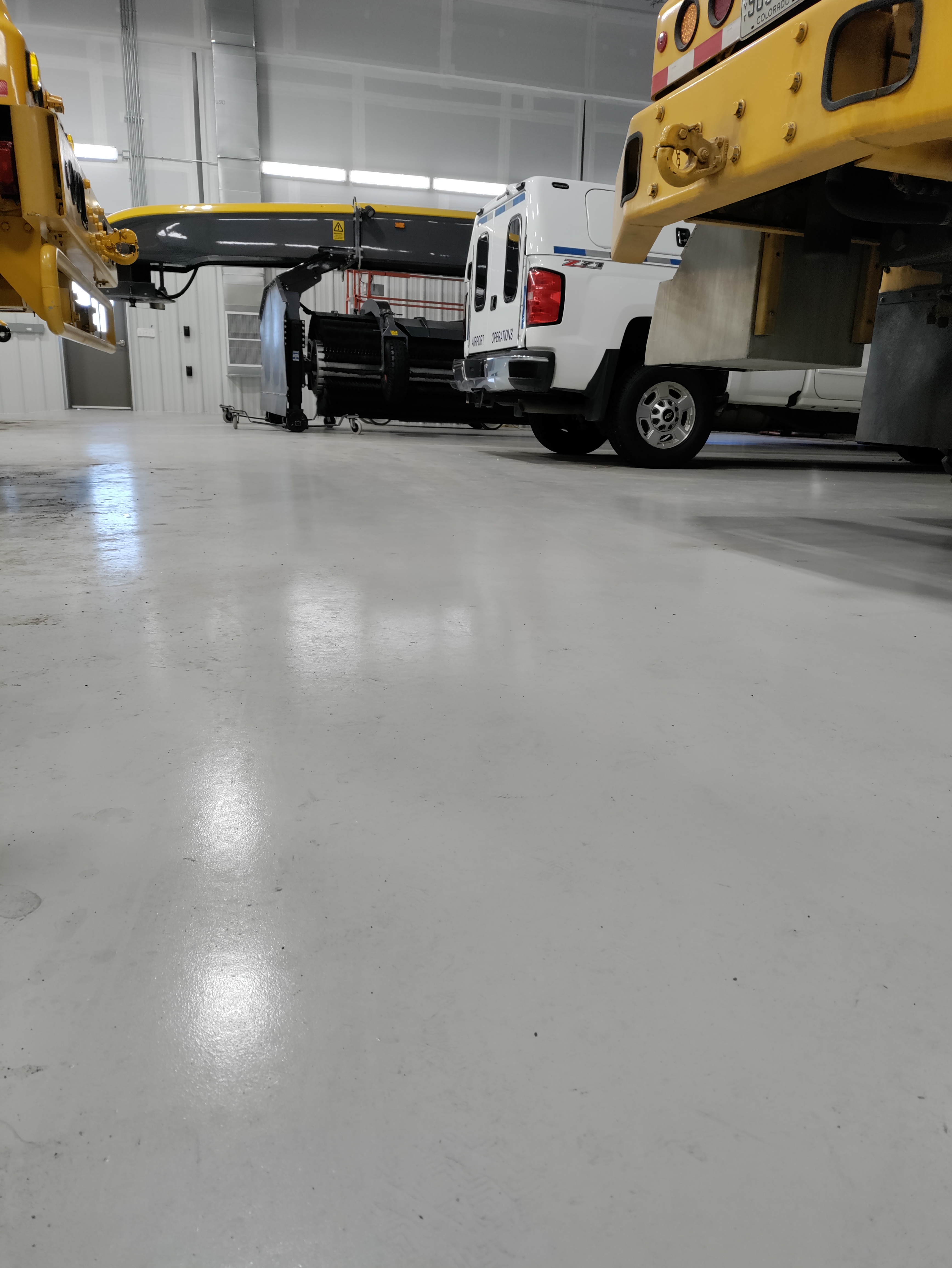 Heavy-duty epoxy floor in airport operations facility with heavy equipment — industrial epoxy flooring Colorado