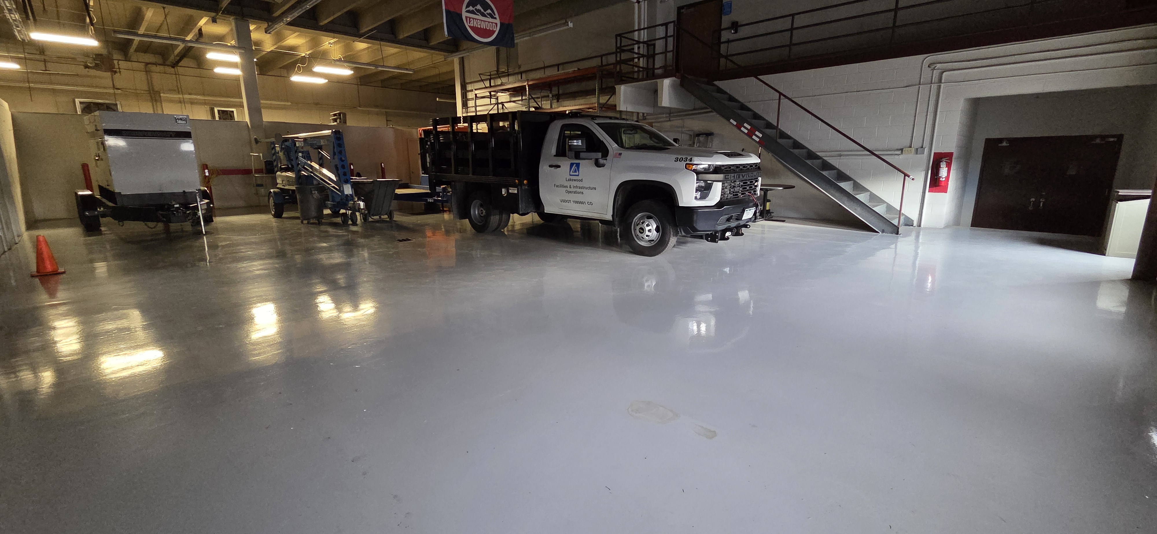 Epoxy floor coating in Lakewood municipal facilities garage with work vehicles — commercial epoxy Colorado