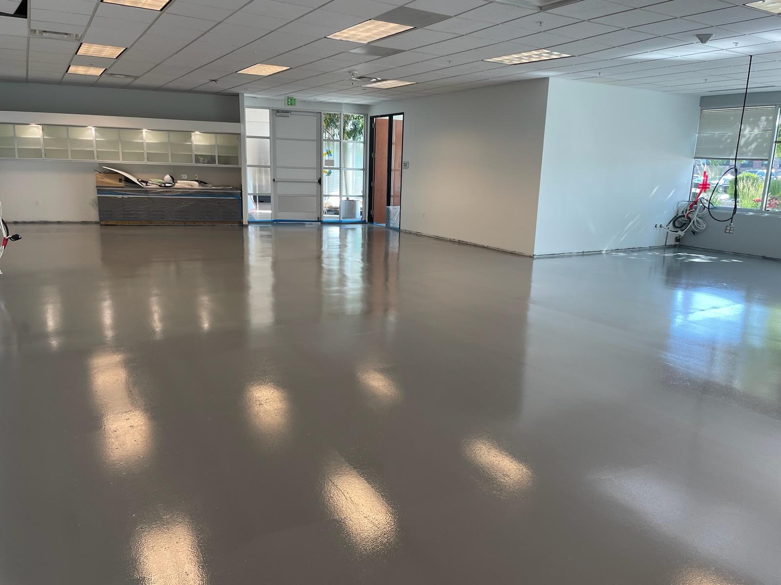 Commercial showroom with glossy epoxy floor coating and glass garage doors — commercial epoxy Denver