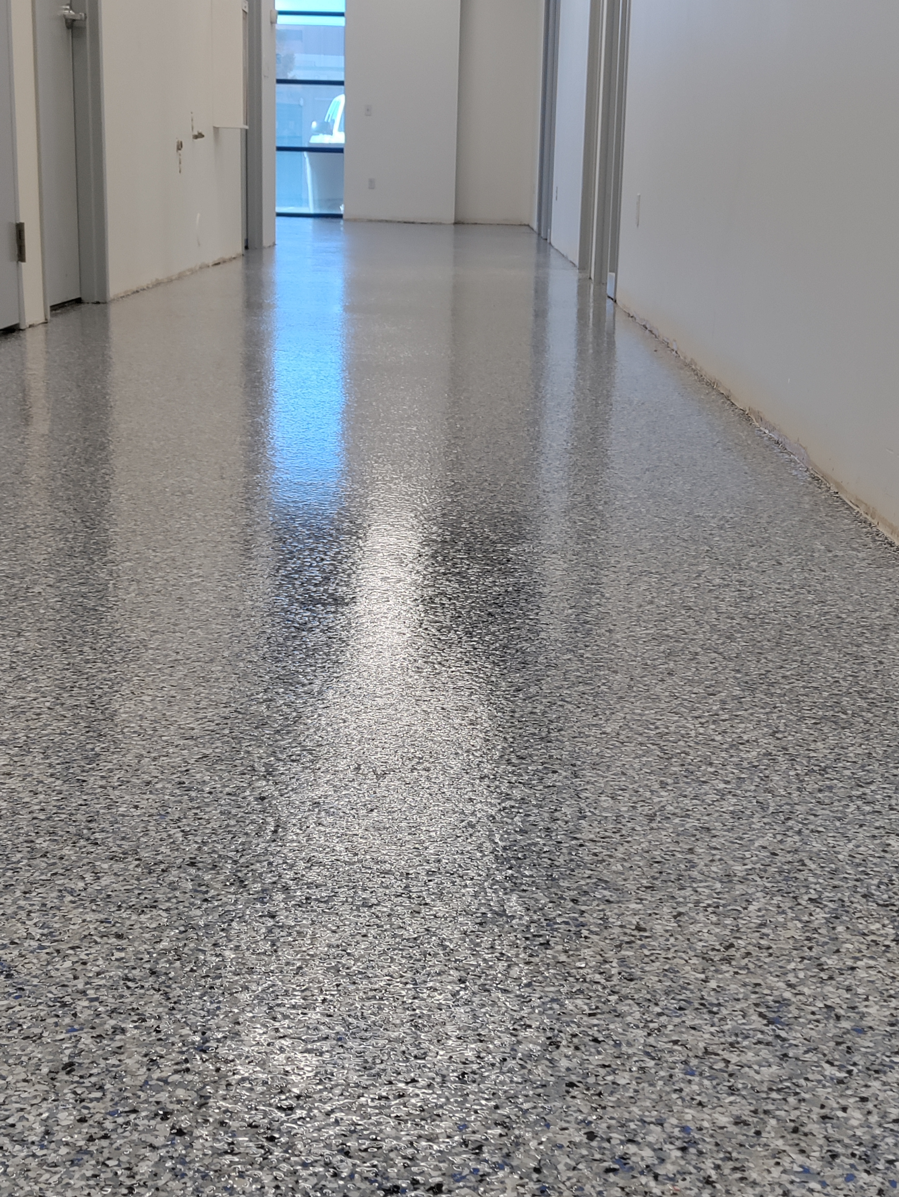 Glossy flake epoxy corridor reflecting overhead lights in commercial facility