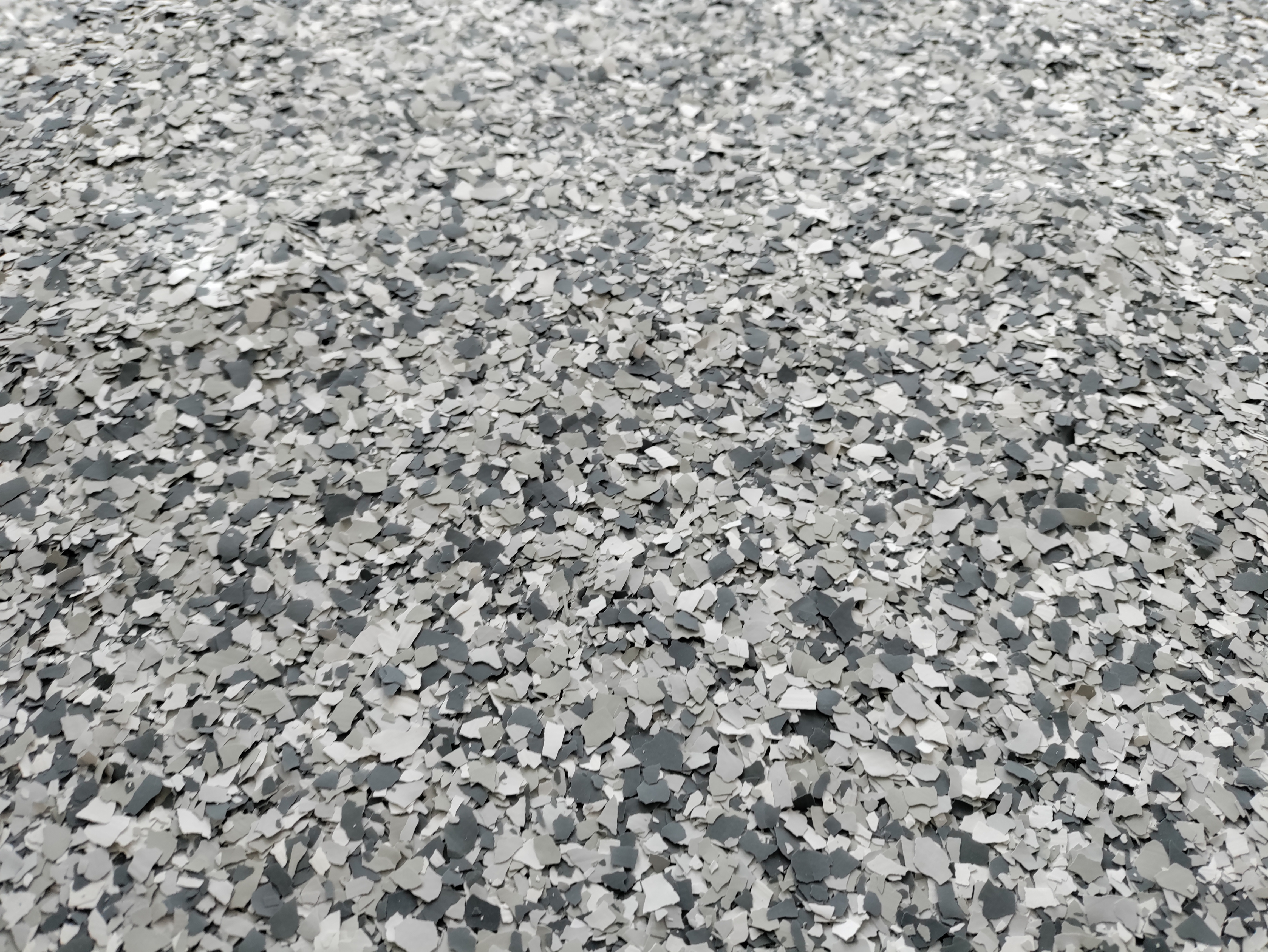 Close-up detail of gray full-broadcast decorative flake chip pattern before topcoat