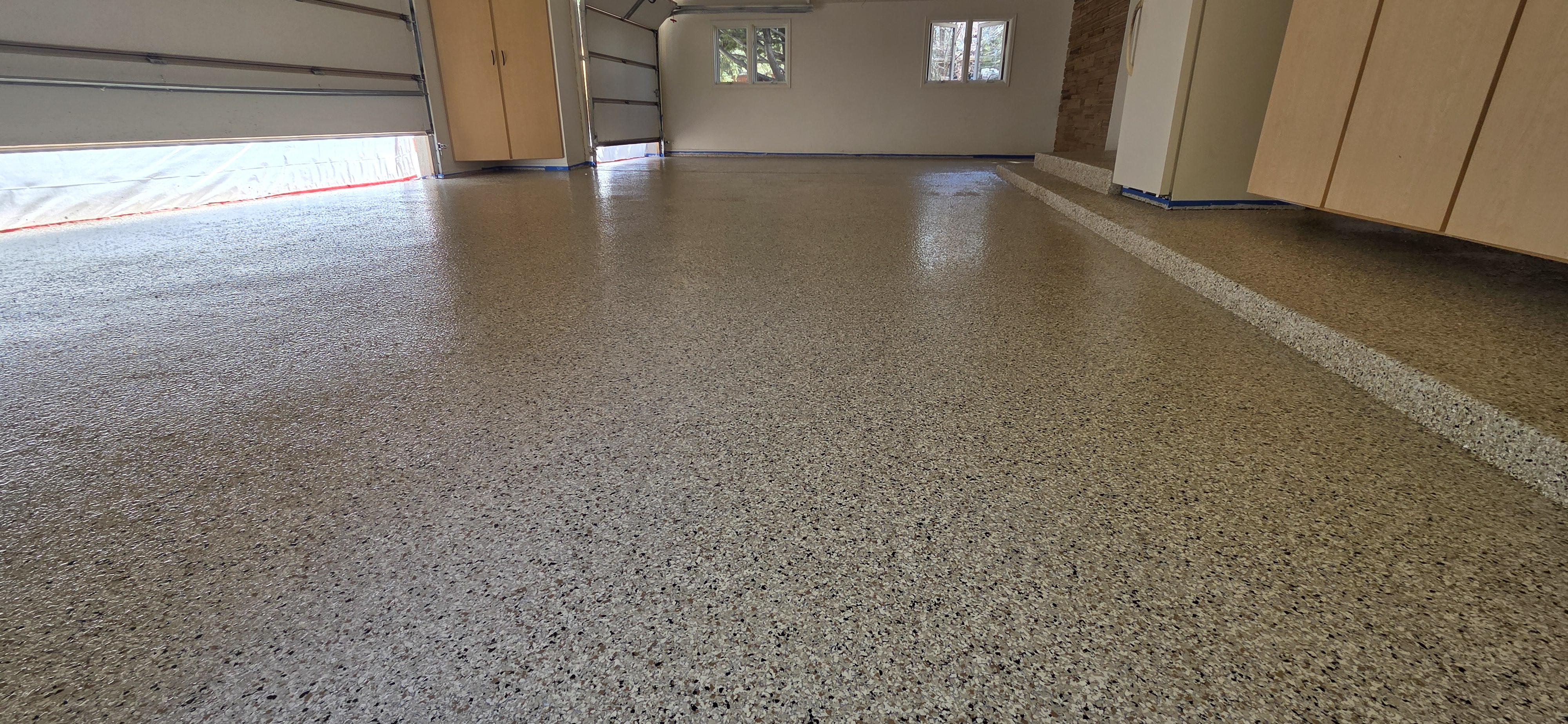 Full-broadcast flake epoxy in spacious three-car residential garage — flake epoxy garage Colorado
