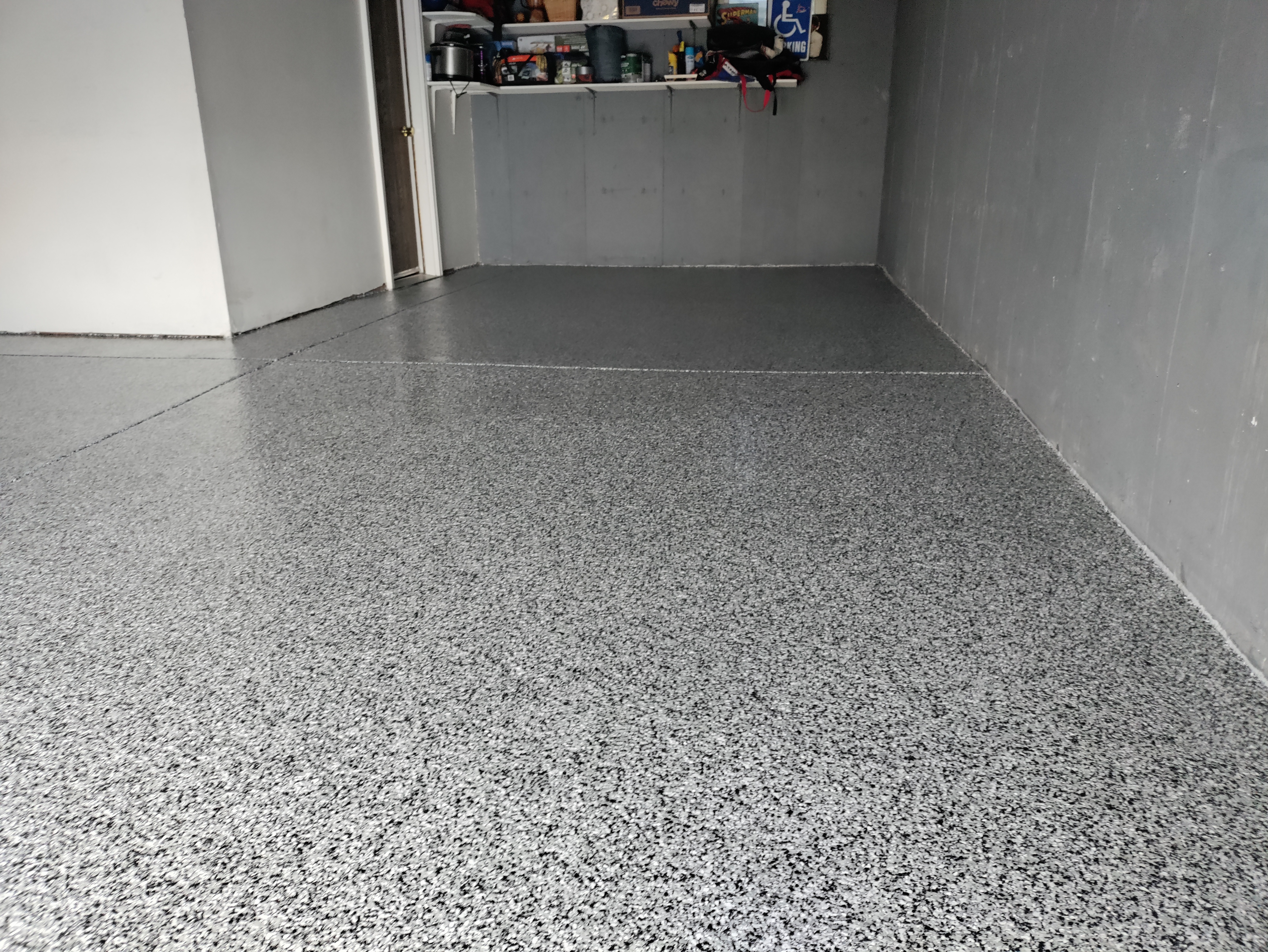 Single-car garage with gray flake epoxy floor coating and storage shelving — garage epoxy Denver