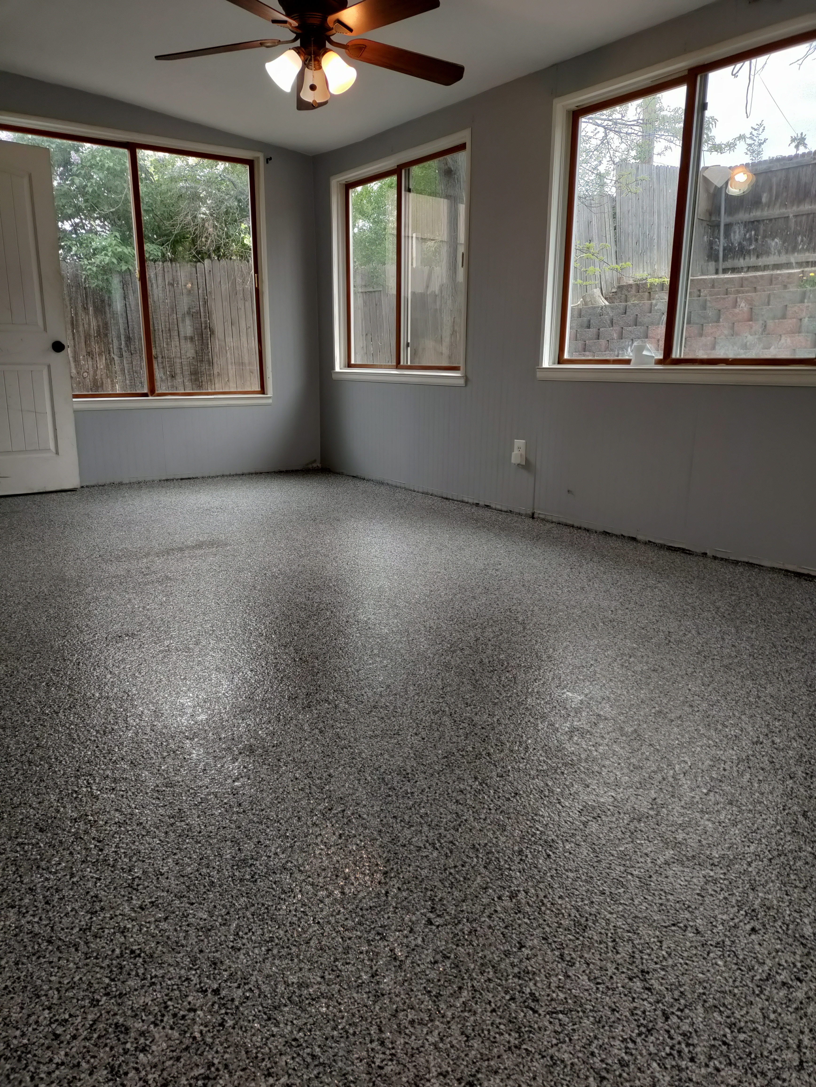 Completed flake epoxy floor in residential sunroom with ceiling fan and natural light