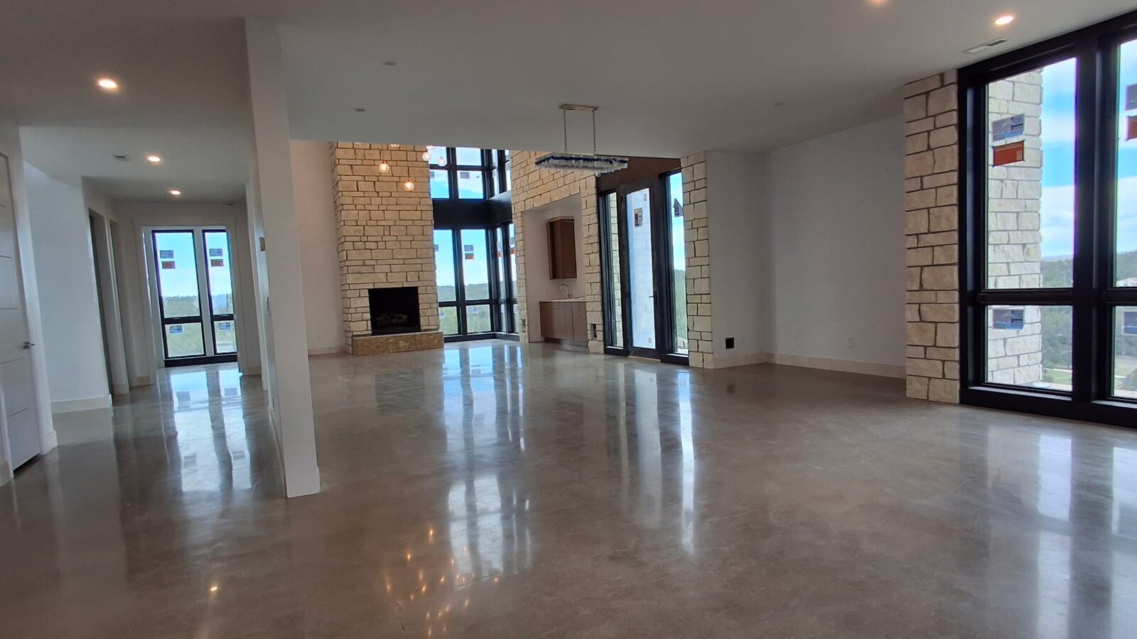 Polished concrete floor in luxury home with stone fireplace and chandelier — residential polished concrete Colorado