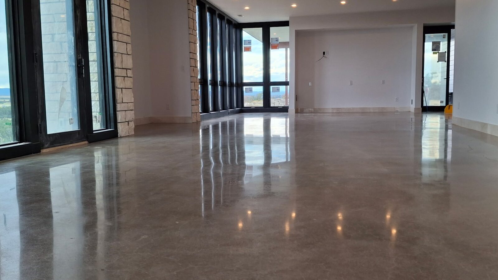 Polished concrete in open-plan living area with stone fireplace surround