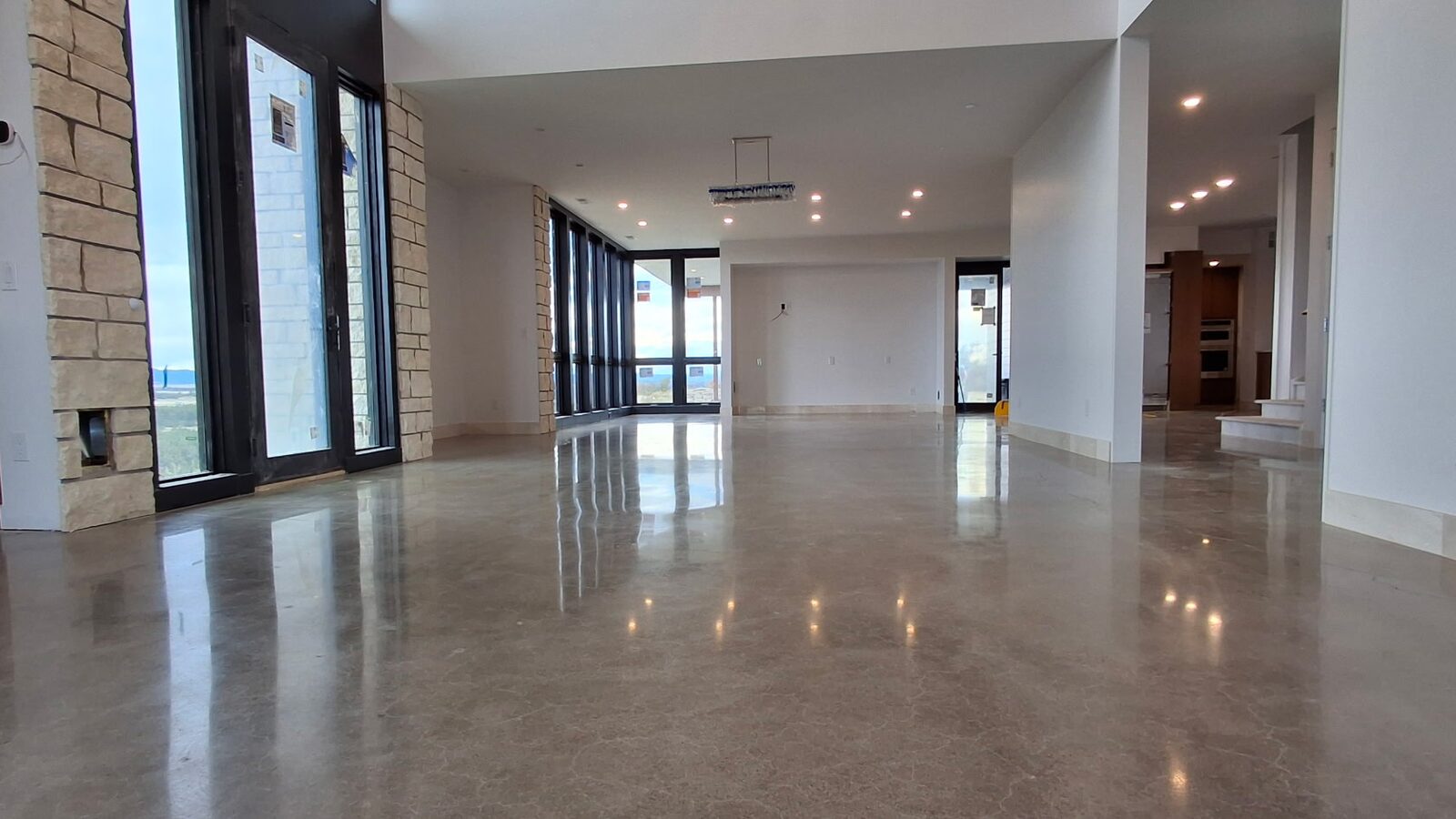 Polished concrete great room with stone walls and floor-to-ceiling windows — new construction polished concrete Denver
