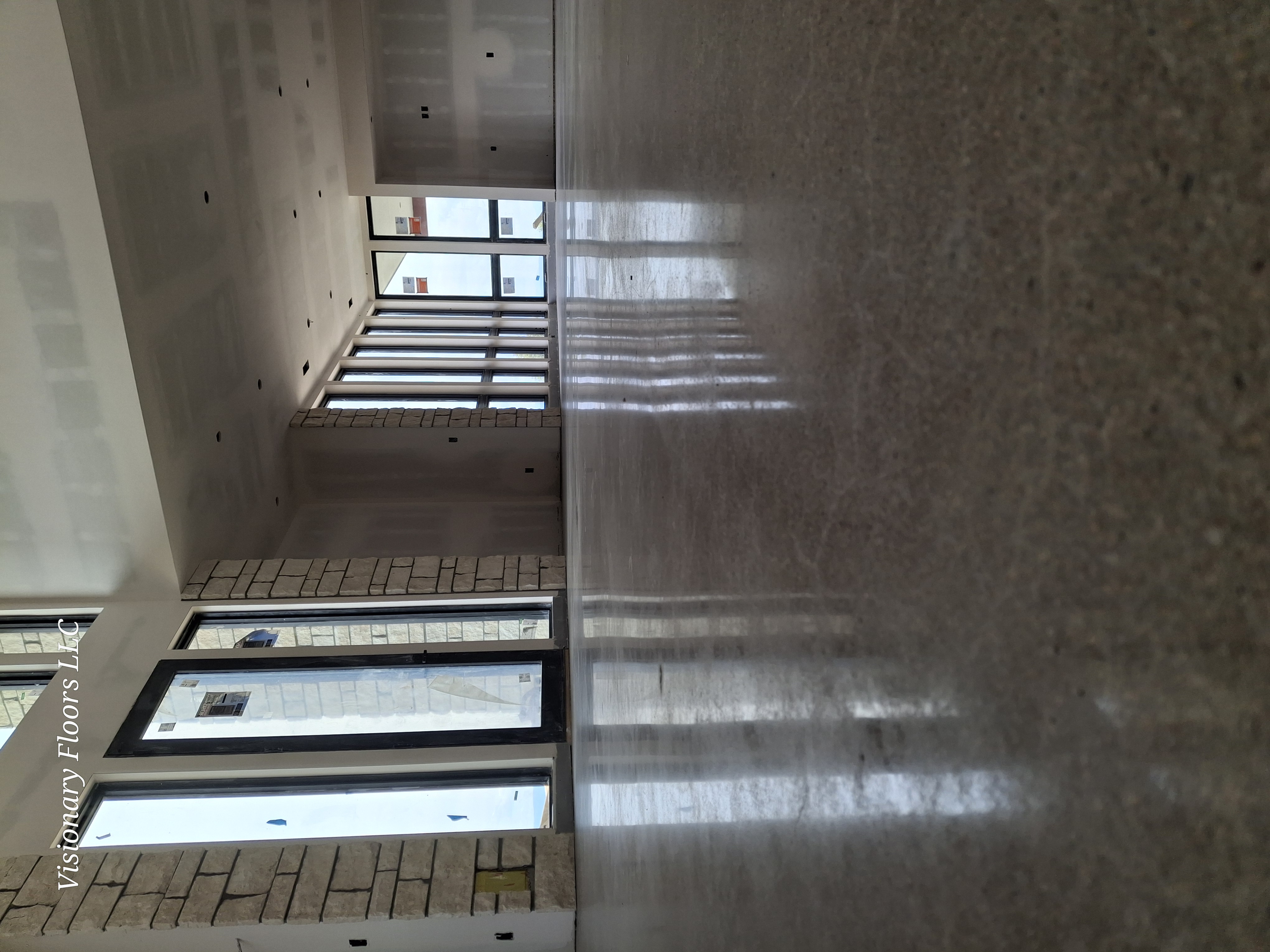 Low-angle view of polished concrete floor with stone columns and natural light