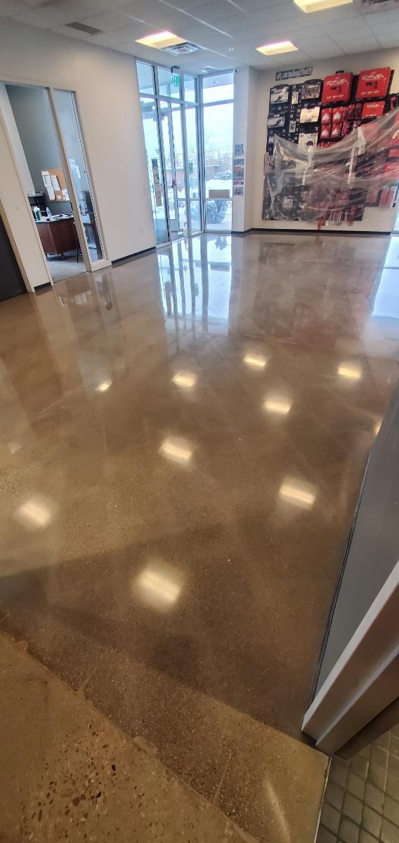 High-gloss polished concrete in retail store reflecting overhead lights — commercial polished concrete Denver