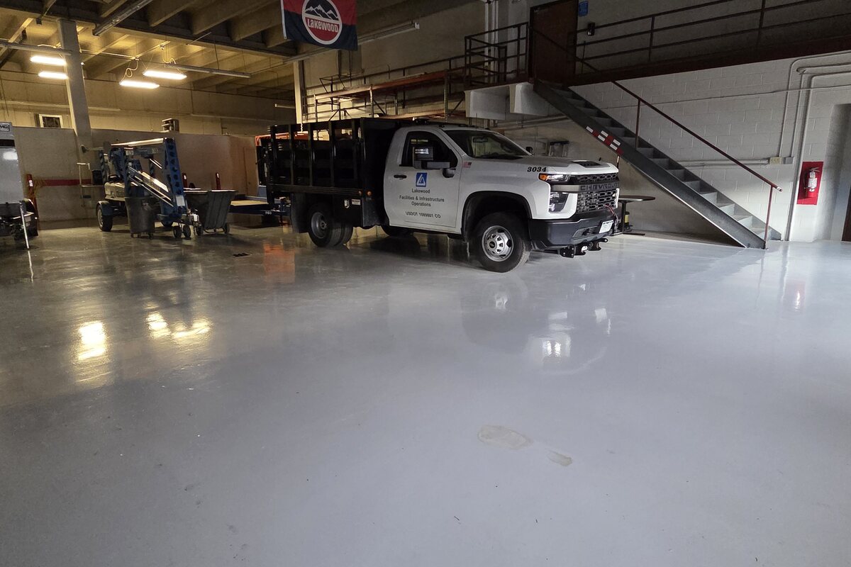 Gray traffic coating in a municipal vehicle bay with work truck on a glossy floor — traffic coatings Denver CO