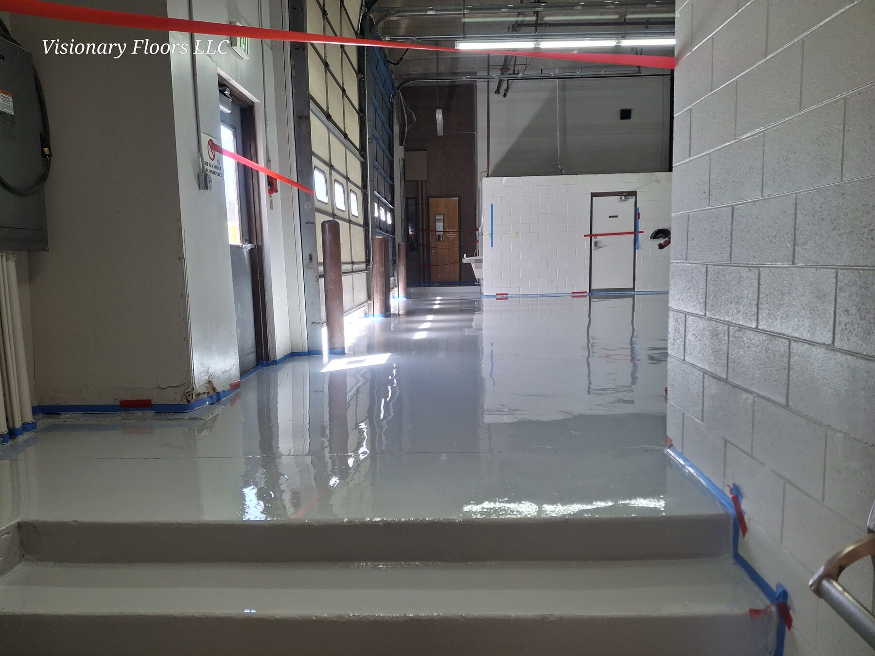 High-gloss gray traffic coating in an industrial corridor with coated steps — traffic coatings Denver CO