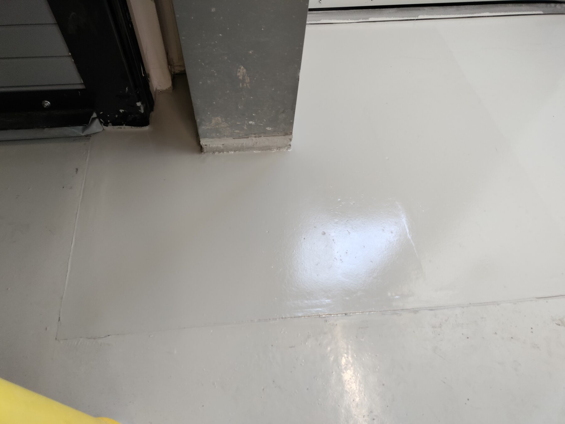 Close-up of gray traffic coating finish at an overhead door threshold — seamless traffic coating detail Denver