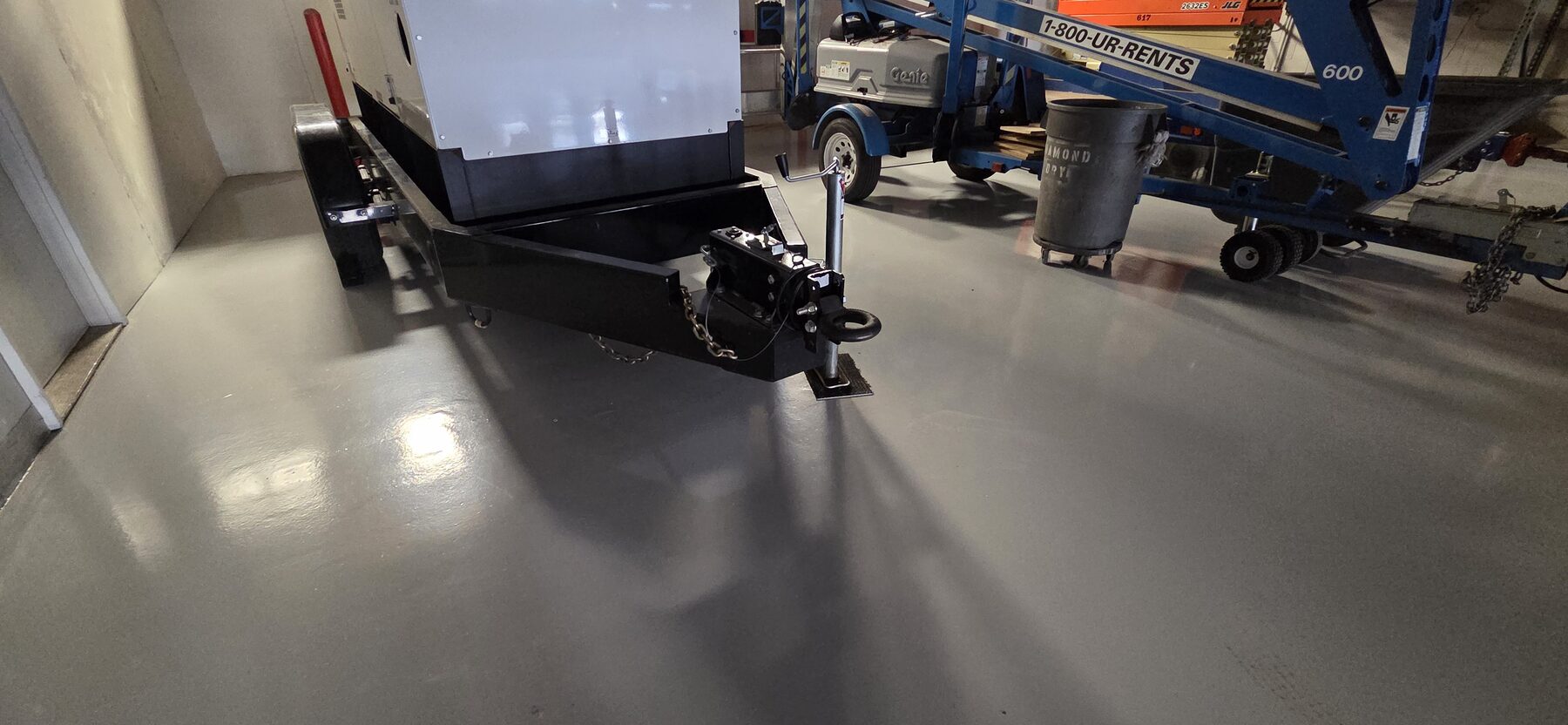 Durable gray traffic coating under generator trailer and lift equipment in municipal garage — industrial floor coating Denver