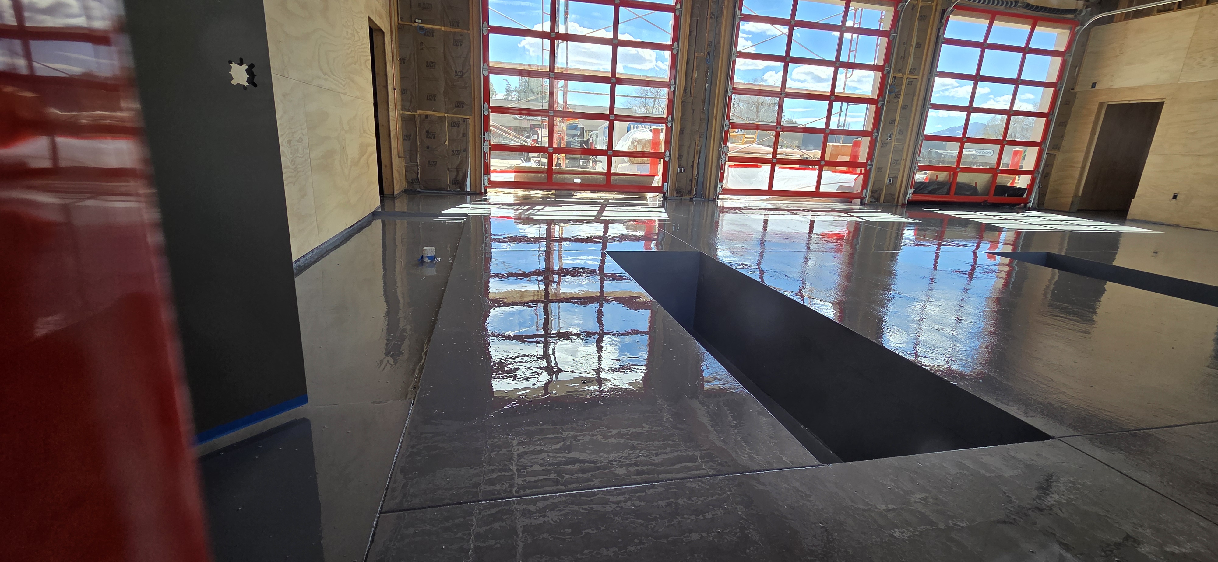 Traffic coating in fire station bay with red apparatus doors and vehicle pit — traffic coatings Colorado