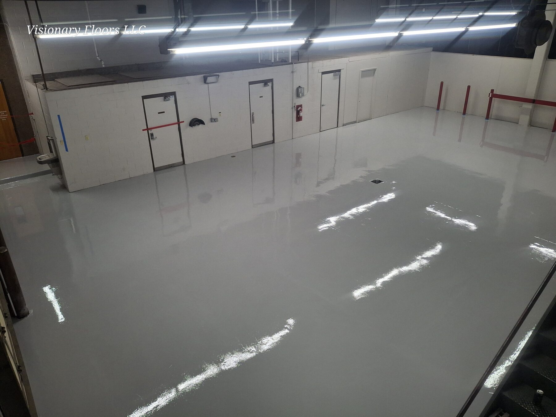 Reflective gray traffic coating in a large interior facility bay with safety bollards — commercial traffic coatings Colorado