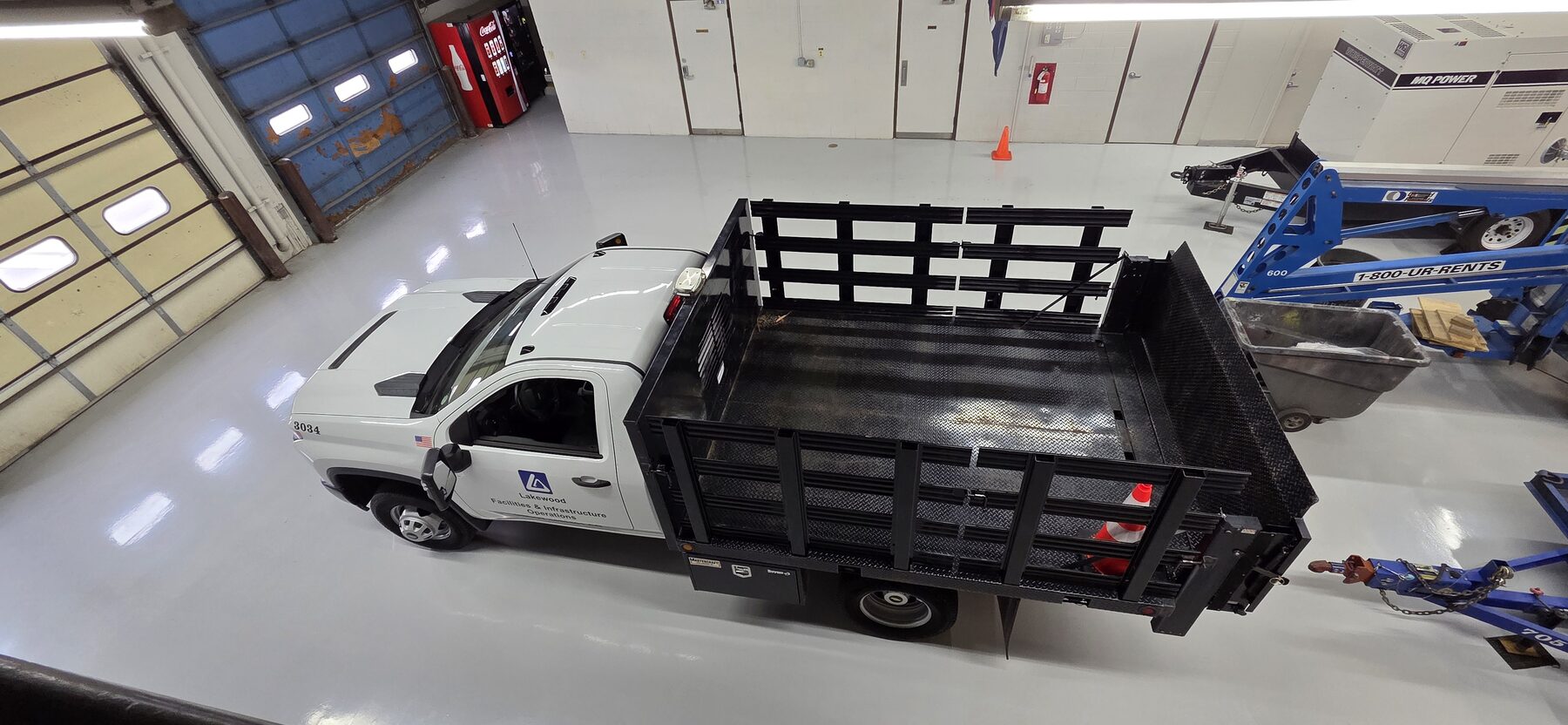 Gray traffic-coated floor in municipal garage with stake-bed truck and lift equipment — durable floor coating Denver